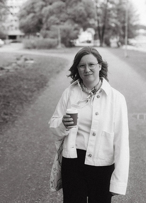 Ancreo Oy:n yrittäjä ja graafinen suunnittelija Anna Ahonen puistossa kävelemässä take away-kahvikuppi kädessä.